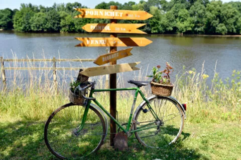Un vieux vélo est posé sur un panneau indiquant plusieurs directions
