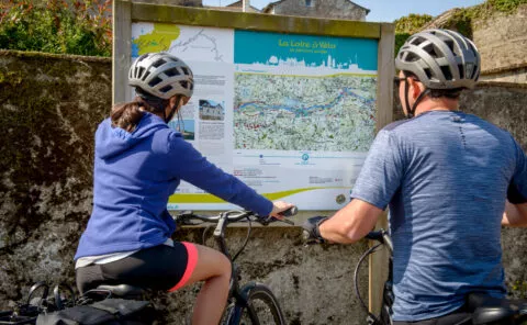 Deux cyclotouristes s'informe devant un panneau relais info service de la Loire à Vélo