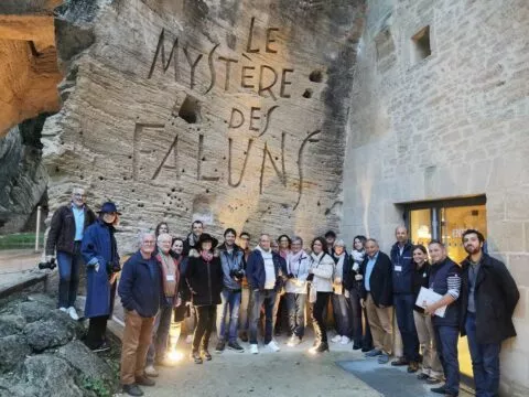 Groupe de superfans et organisateurs, devant la paroi blanche, gravé avec le nom du site : Le Mystère des faluns.