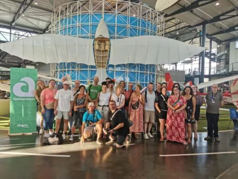 Groupe de trente personnes environ dans le musée Espace air passion, posant au milieu des avions exposés.
