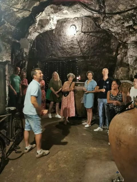 Un dizaine de visiteurs dans les caves troglo. Au milieu, le vigneron anime le groupe.
